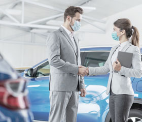 Dos personas dándose la mano en un concesionario de coches