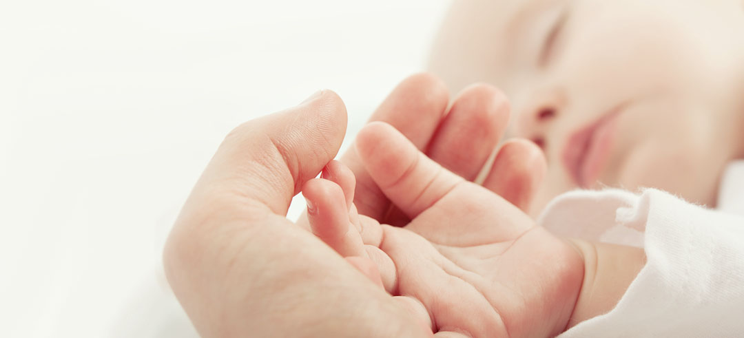 Mano de un bebé sobre una mano adulta