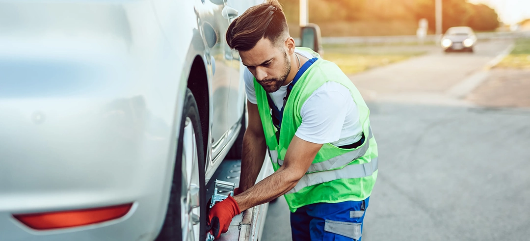 Chico realizando asistencia en carretera a un coche averiado