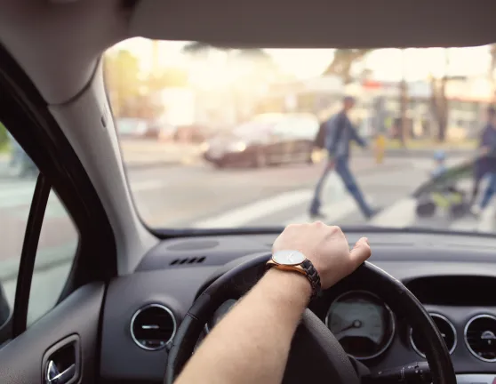 Persona conduciendo mientras cede el paso a peatones